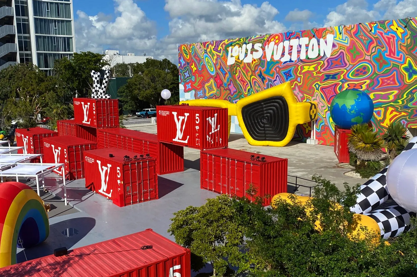 Outdoor brand activation built from stacked printed shipping containers with an oversized sunglasses sculpture on the plaza