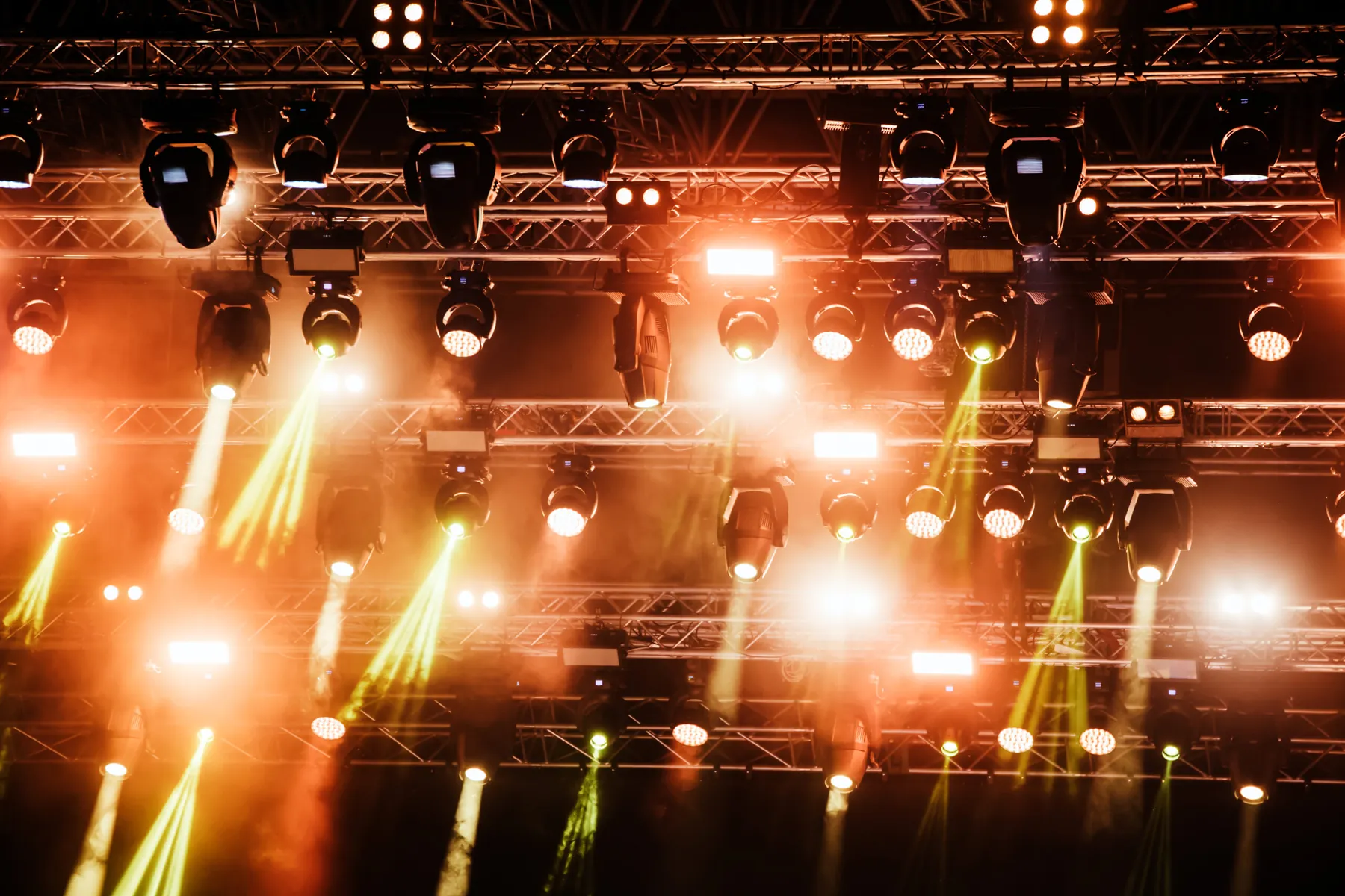 Bright stage lighting cutting through haze above a concert stage