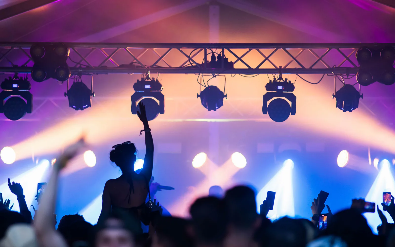 Overhead truss loaded with moving lights and pars above a crowd, beams cutting through haze