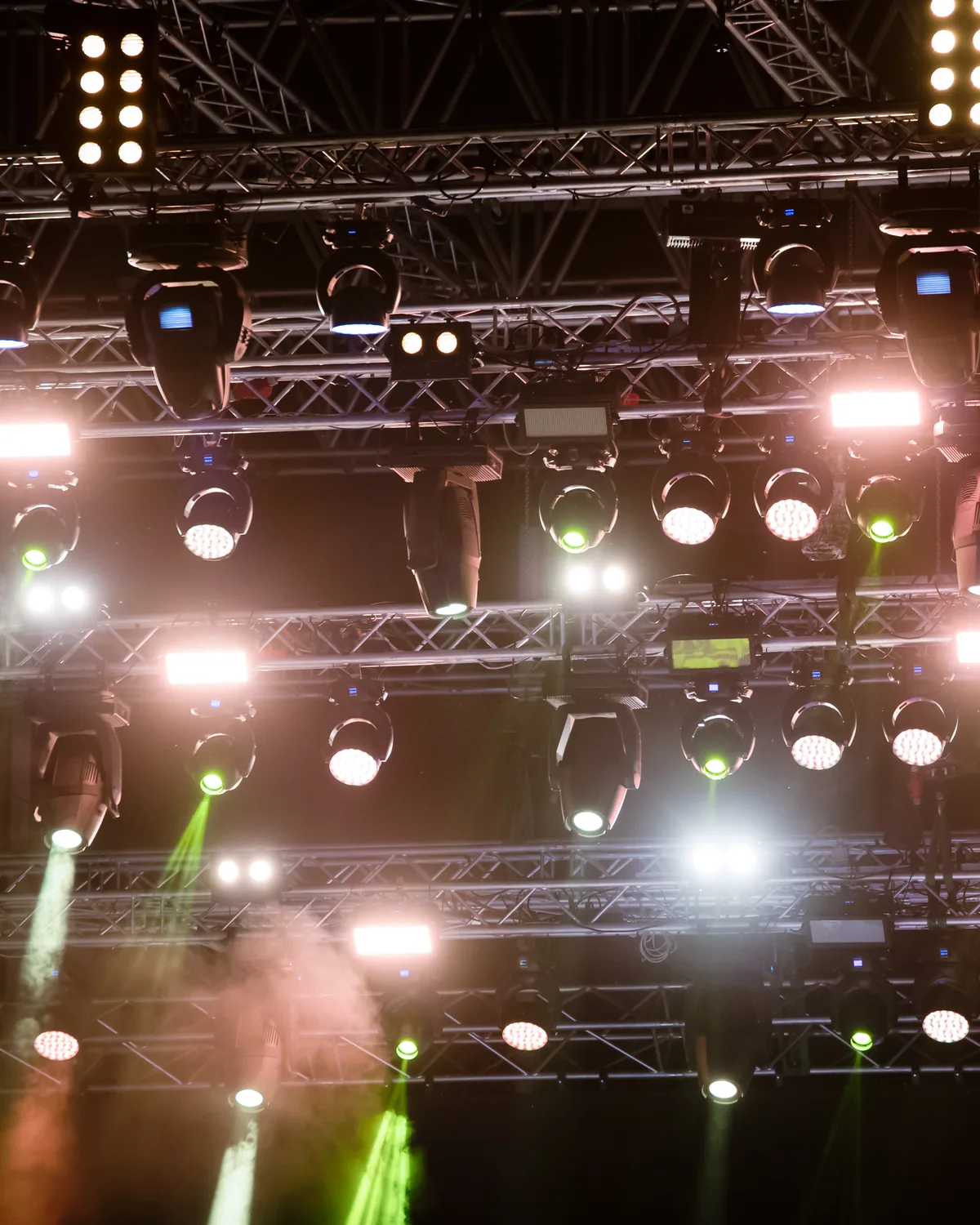 Overhead truss grid loaded with moving heads, pars and strobes, beams and haze cutting down through it